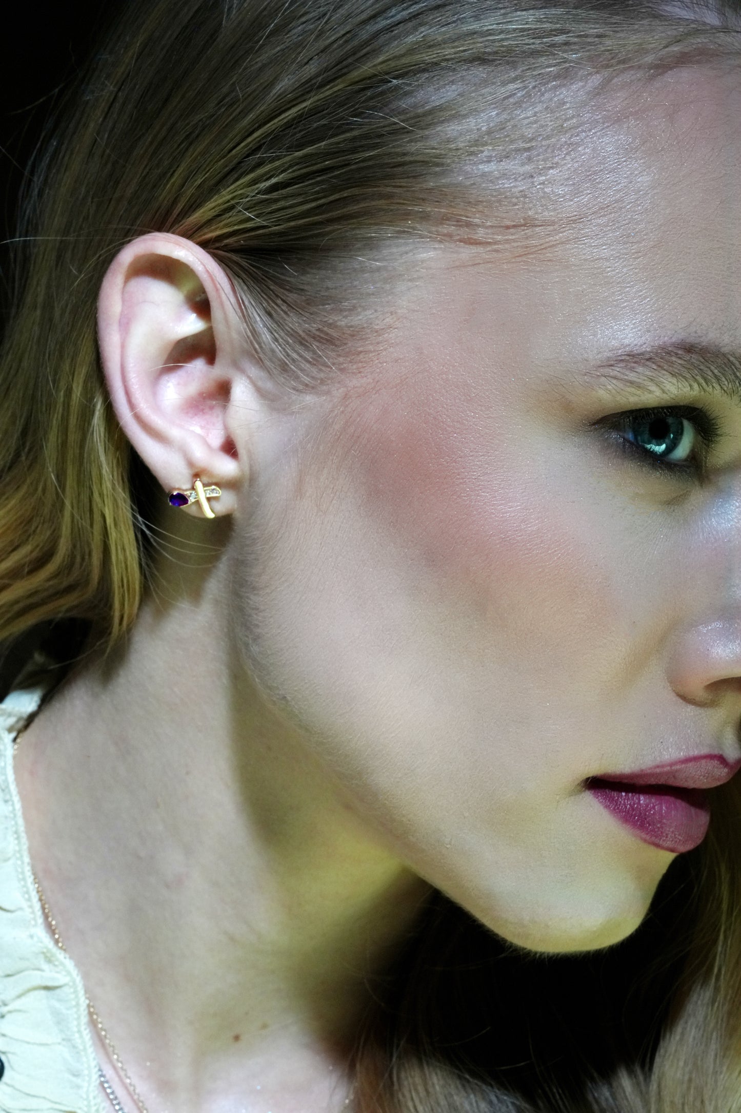 Close-up showcasing Celestial Blue Earrings on a woman's ear; gold and blue gemstone detail adds elegance to the jewelry.