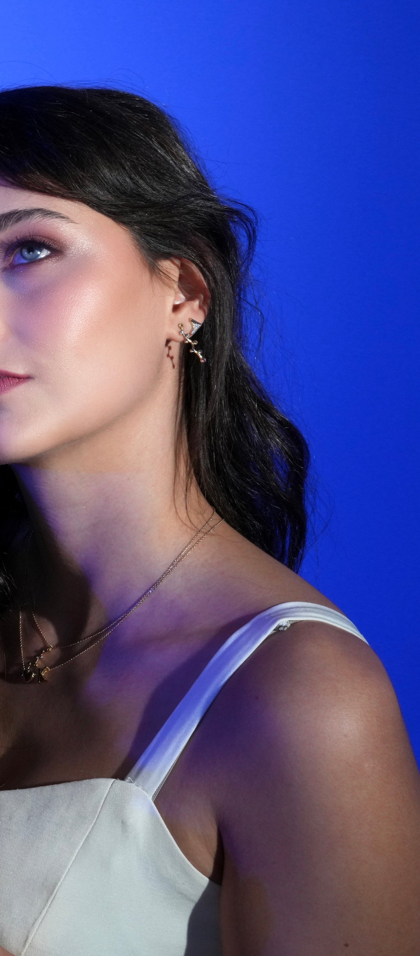 Model wearing Cosmic Lights earrings; a dainty, celestial-inspired gold earring design with gemstones.